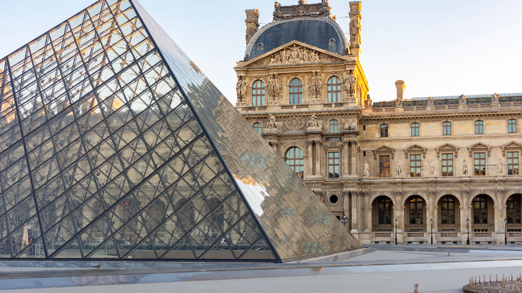 Tourist couple on open-top bus viewing illuminated Louvre pyramid at night Paris